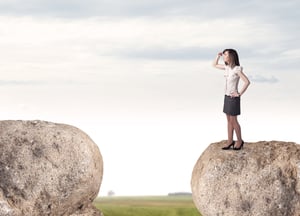 Young businesswoman standing on edge of rock mountain